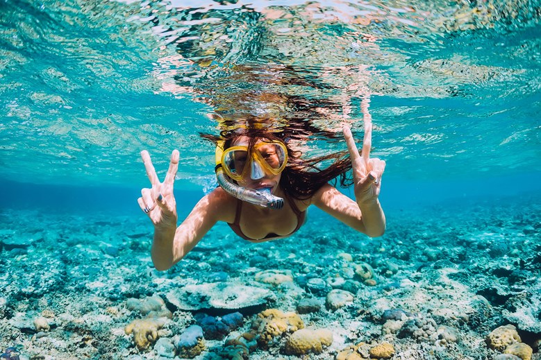 girl snorkeling in shallow water and looking into camera