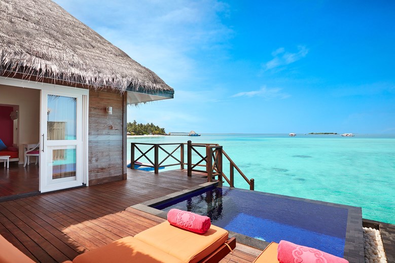 the deck of an overwater villa on the ocean. the deck has an infinity pool and chairs