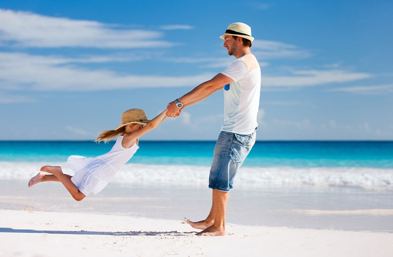 dad swinging daughter in the air on the beach