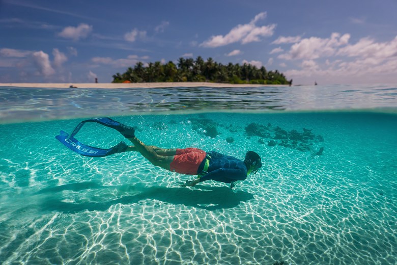 Person snorkeling in shallow water near the shore in the maldives